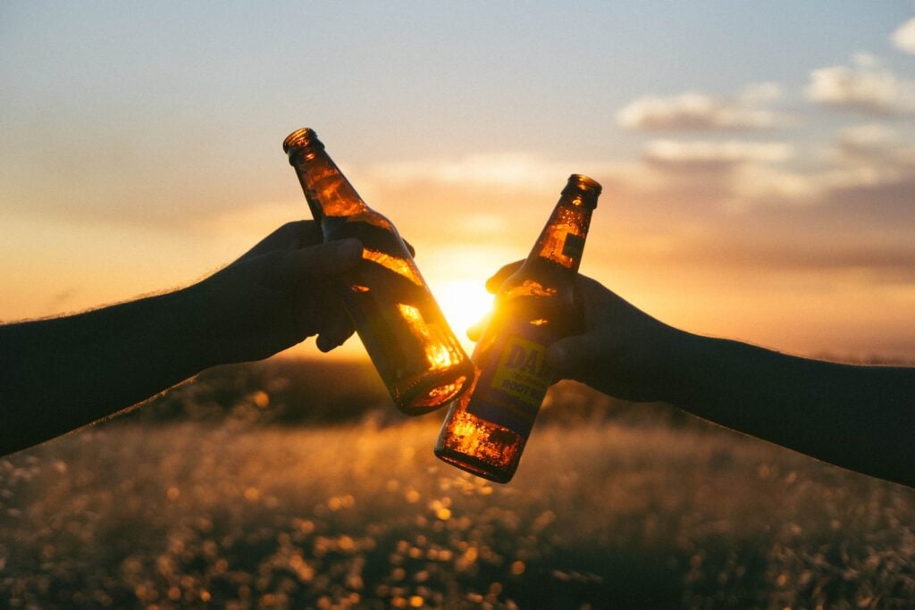 Photography of person holding glass bottles during sunset