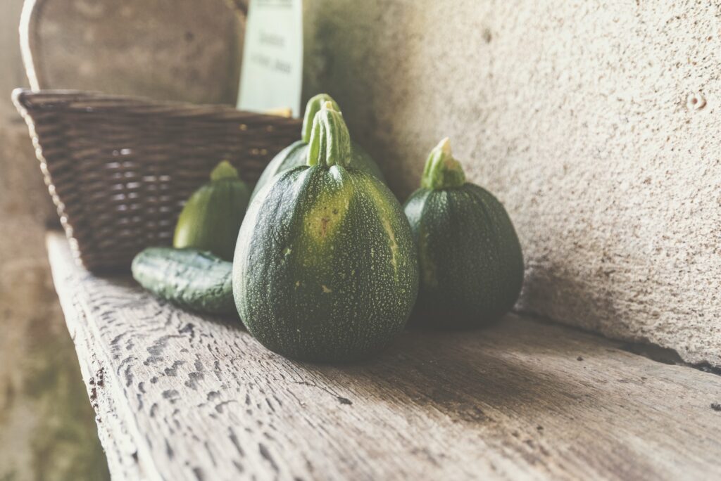 Four green squash on wooden shelf