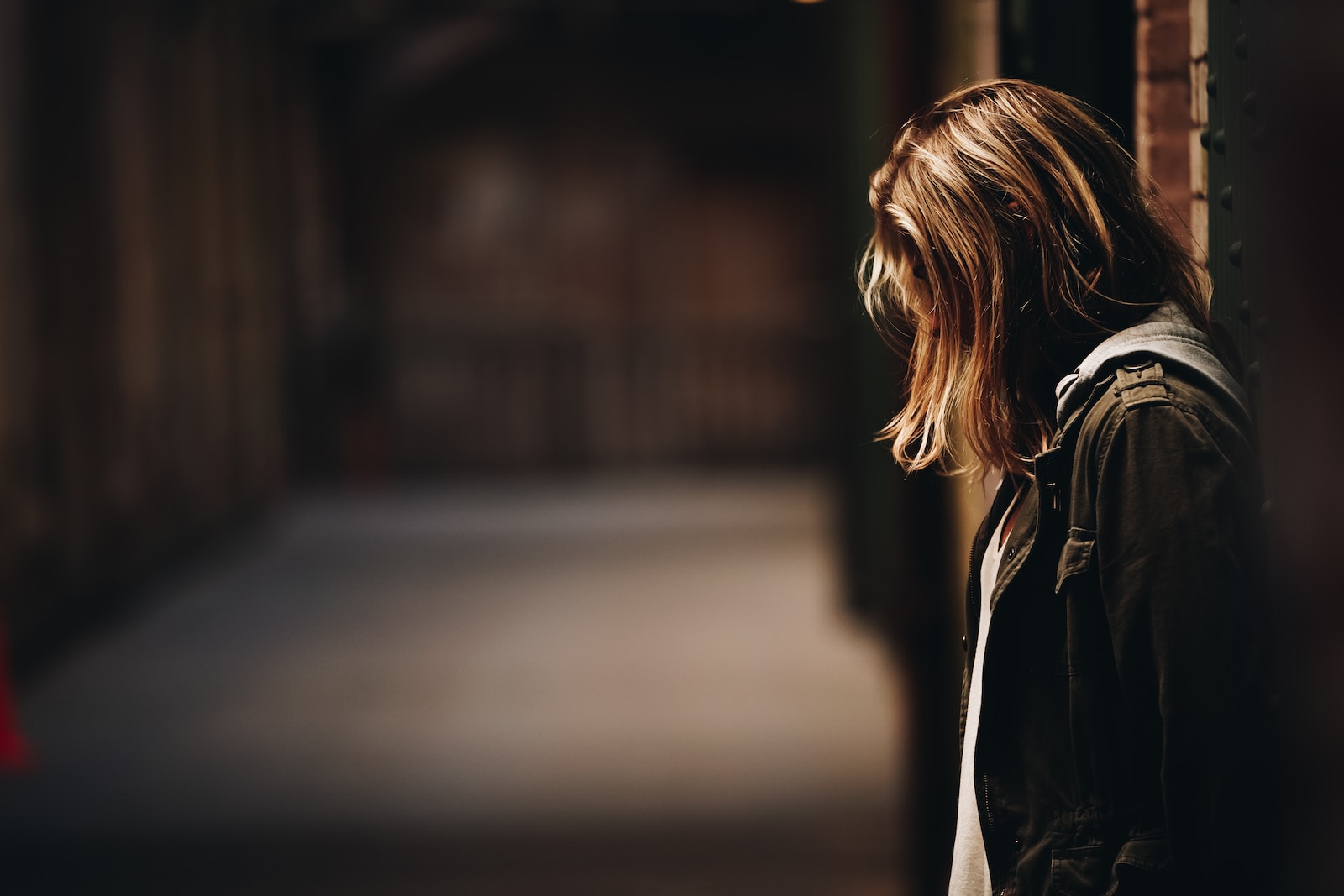 Woman leaning against a wall in dim hallway