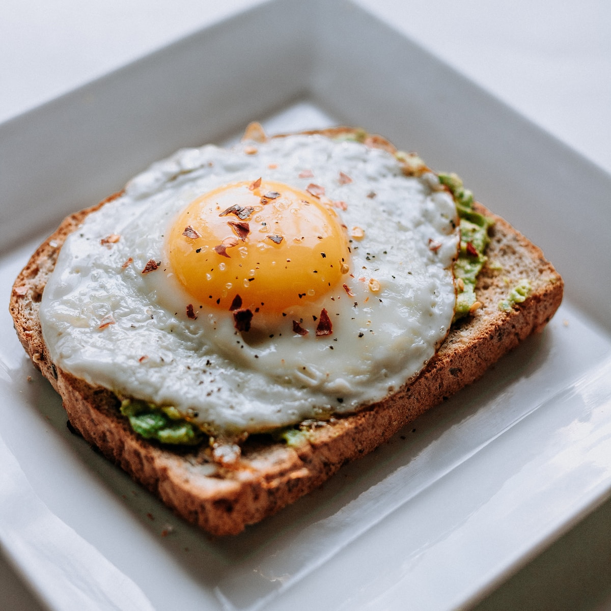 Bread with sunny side up egg served on white ceramic plate