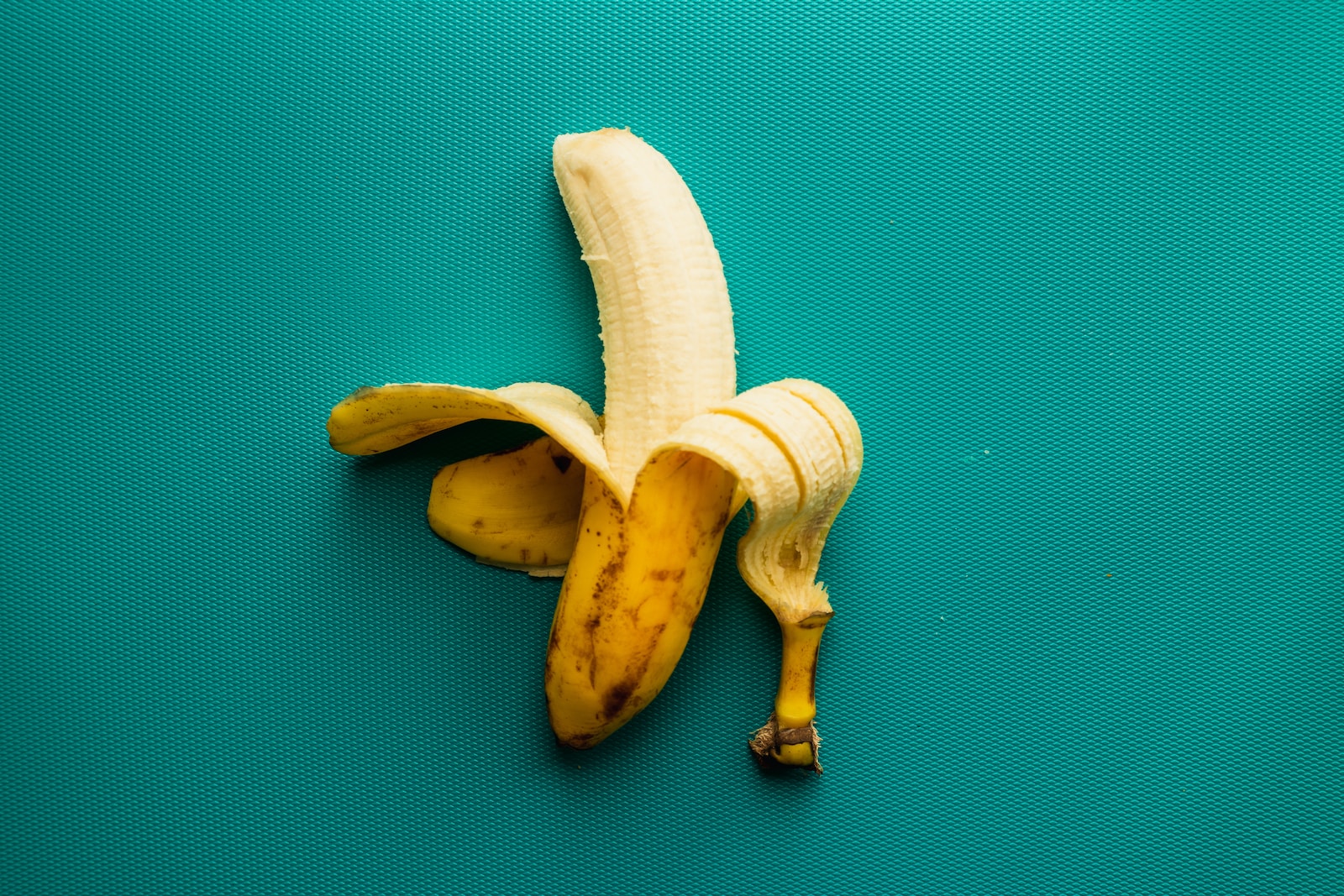 A peeled banana sitting on top of a blue surface