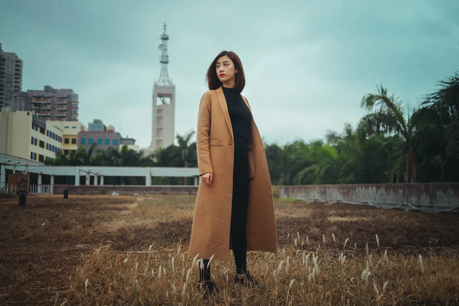 woman wearing brown coat standing on brown grass