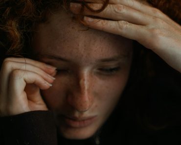 a close up of a person holding their head