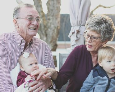 Grandmother and Grandfather Holding Child on Their Lap