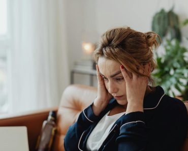 Woman Wearing a Pajama Holding Her Head