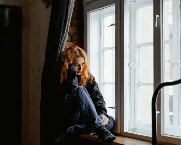 Woman in Black Leather Jacket Sitting on Brown Wooden Floor