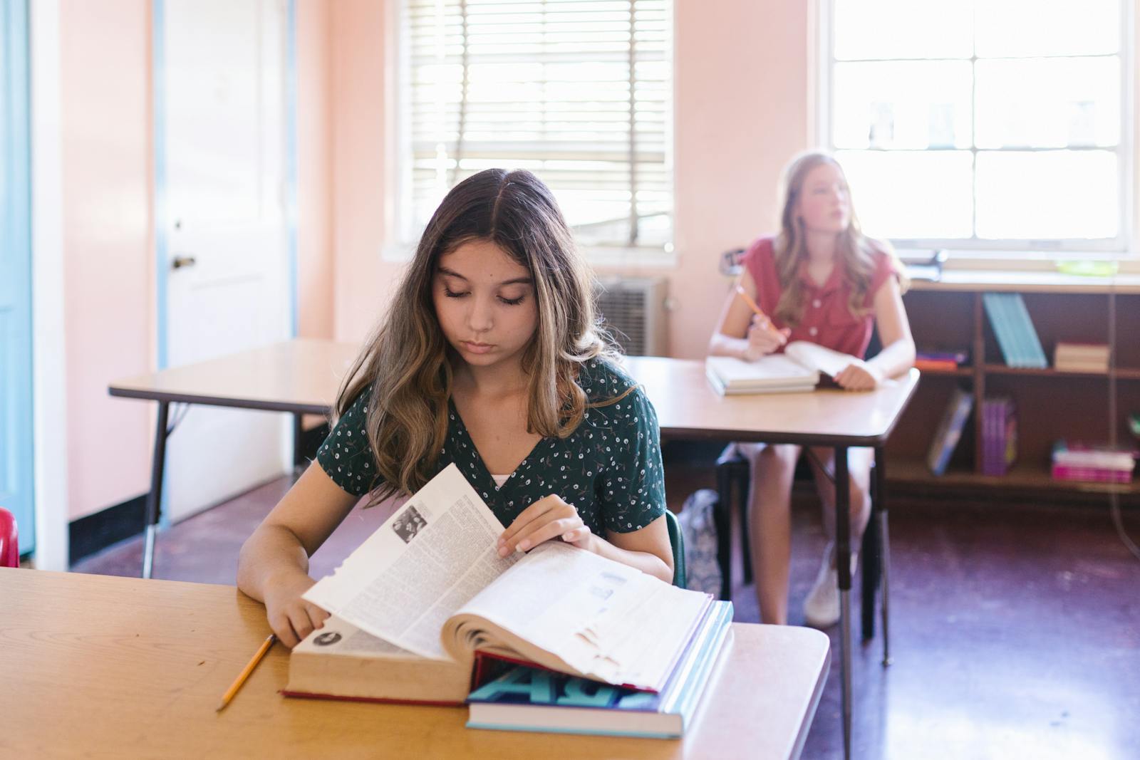 A student reading a book while inside a classroom