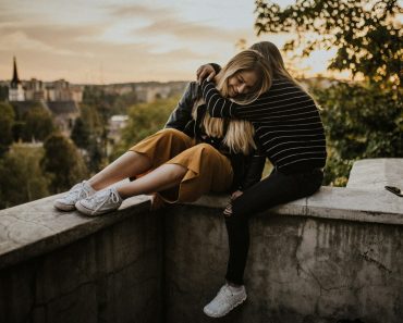 woman in black and white striped long sleeve shirt and brown pants sitting on concrete wall