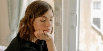 Woman in Black Shirt Leaning on White Wooden Window