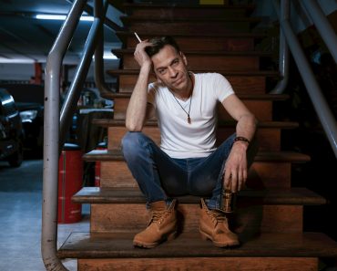 a man sitting on a stair case smoking a cigarette