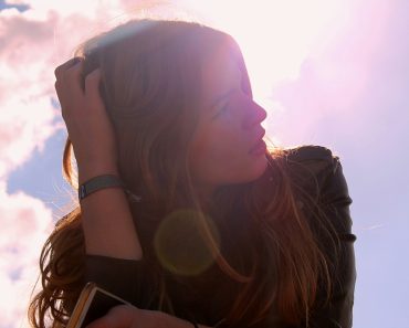 woman in black top holding her hair looking up