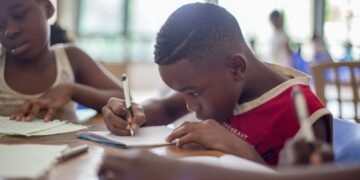 boy writing on printer paper near girl