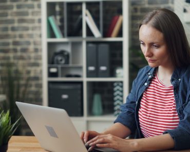 a woman sitting at a table using a laptop computer