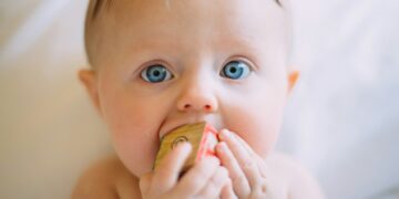 selective focus photography of baby holding wooden cube