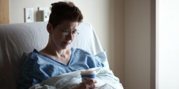 woman on bed holding plastic cup
