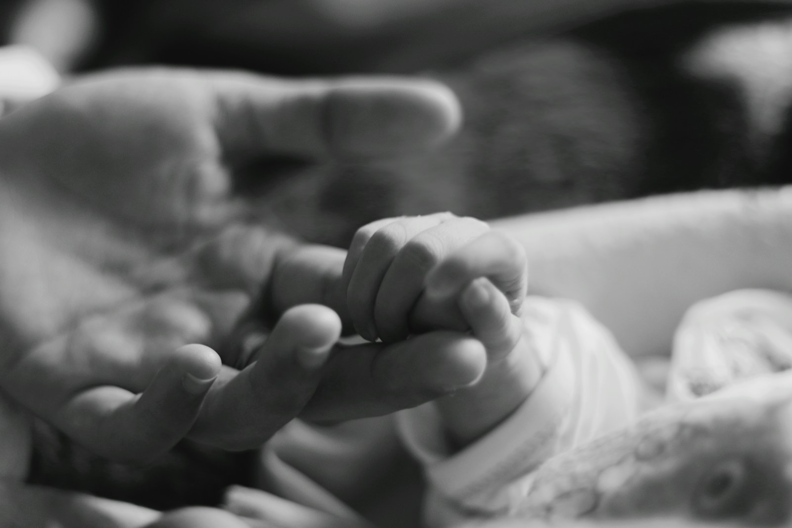 A black and white photo of a person holding a baby's hand