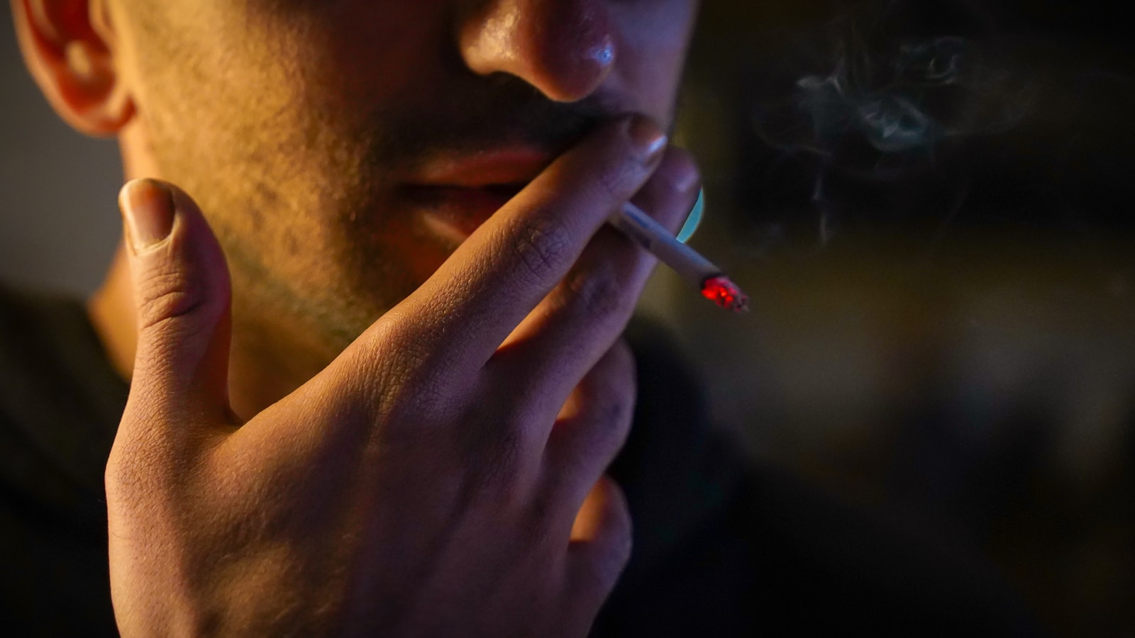 A man smoking a cigarette in the dark