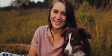woman sitting beside a black and white dog