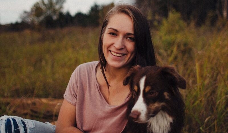 Woman sitting beside a black and white dog