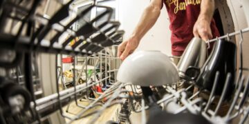 POV perspective of an adult loading dishes into a dishwasher in a home kitchen.