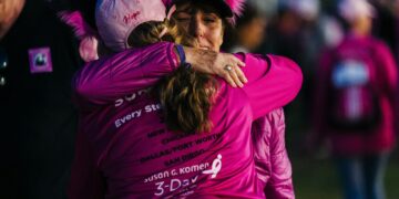 a woman in a pink shirt hugging another woman