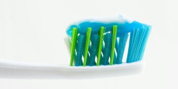 white, blue, and green toothbrush with blue toothpaste