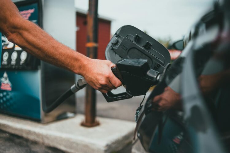 Close up of a hand holding a nozzle while refueling a car at a gas station