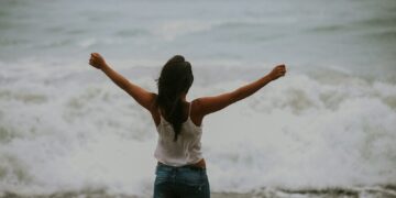 woman in white spaghetti strap top standing on the seashore