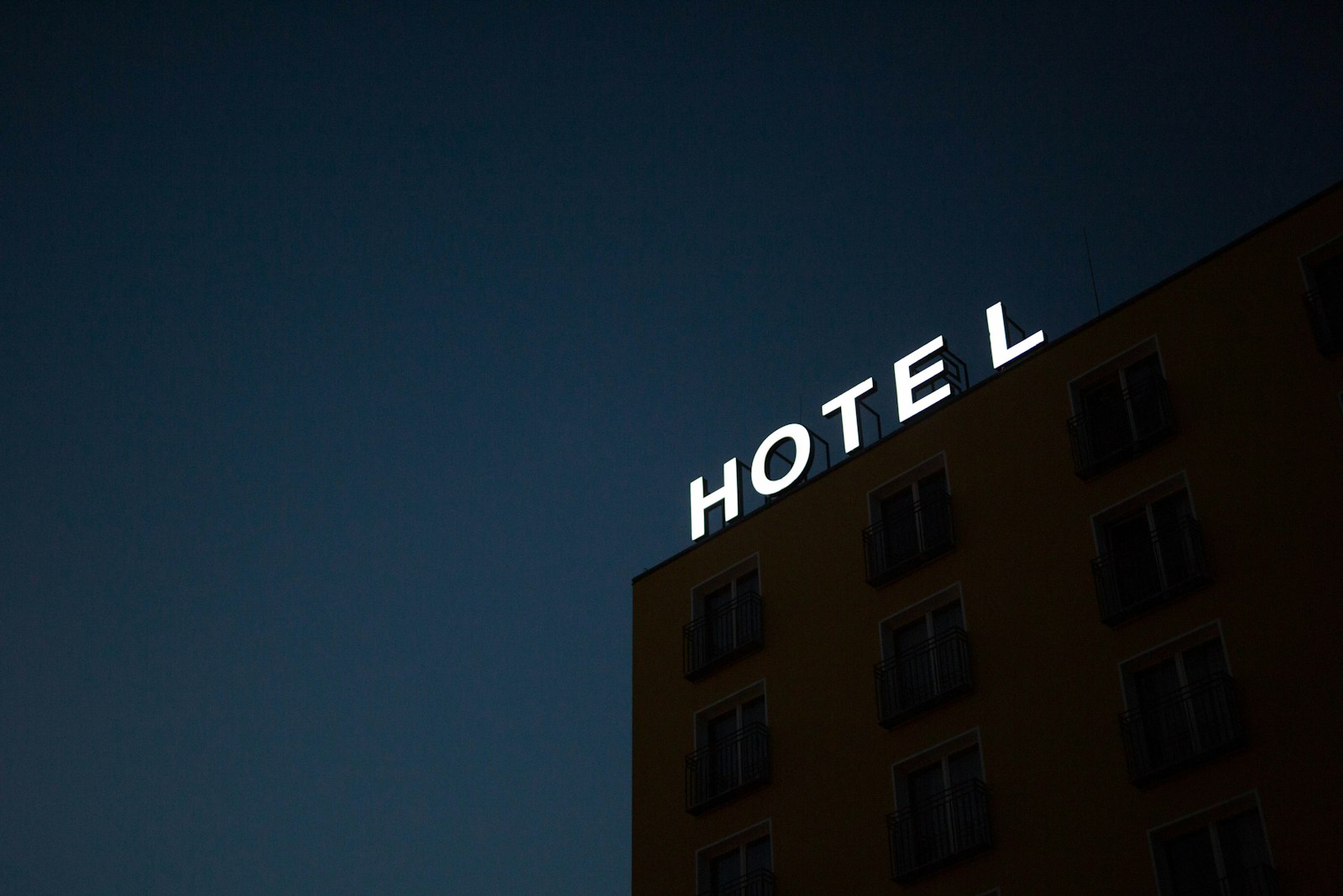 Low angle photo of hotel lighted signage on top of brown building during nighttime