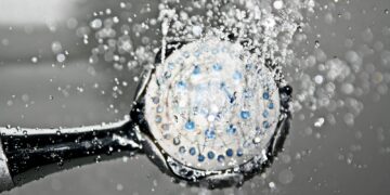 Close-up of a shower head releasing water droplets, creating a crisp and refreshing bathroom scene.