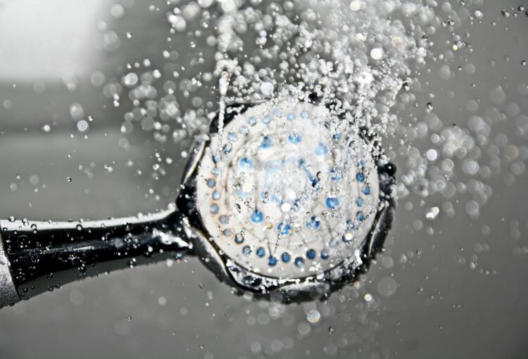 Close up of a shower head releasing water droplets creating a crisp and refreshing bathroom scene