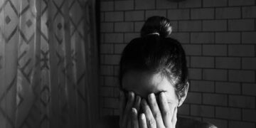 grayscale photo of woman covering her face with her hands