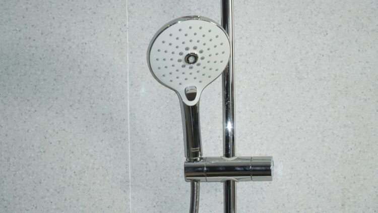 Stainless steel shower head on white ceramic tiles