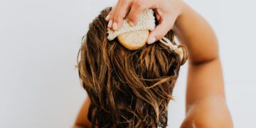 Back view of a person scrubbing their hair with a natural soap bar for a refreshing bath.