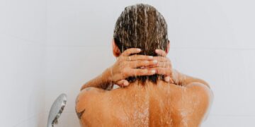 Rear view of a woman enjoying a fresh shower, water streaming down her back.