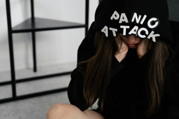 A woman sitting with 'panic attack' on her hood showing anxiety indoors