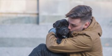 selective focus photography of man hugging black dog