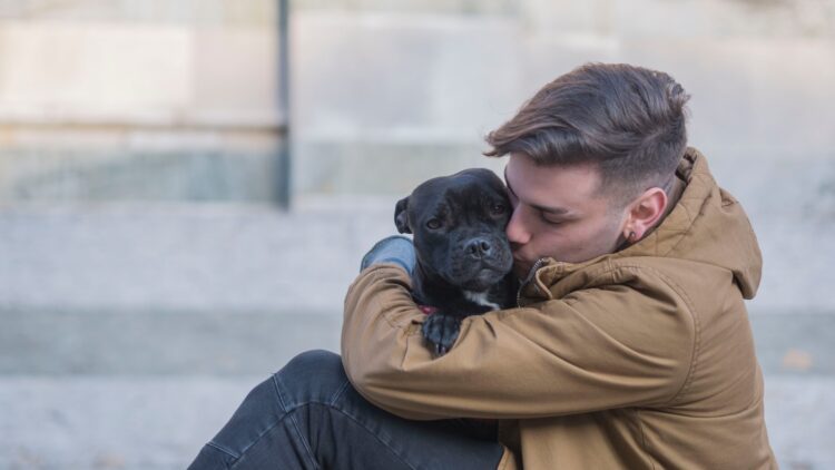 Selective focus photography of man hugging black dog