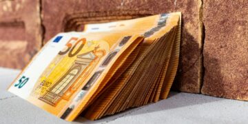 a stack of money sitting on top of a sidewalk