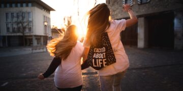 two women walking across the road during sunset
