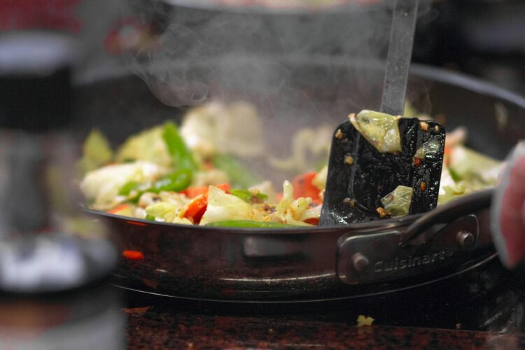 A vibrant stir fry of fresh vegetables sizzling in a pan releasing steam