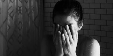 grayscale photo of woman covering her face with her hands