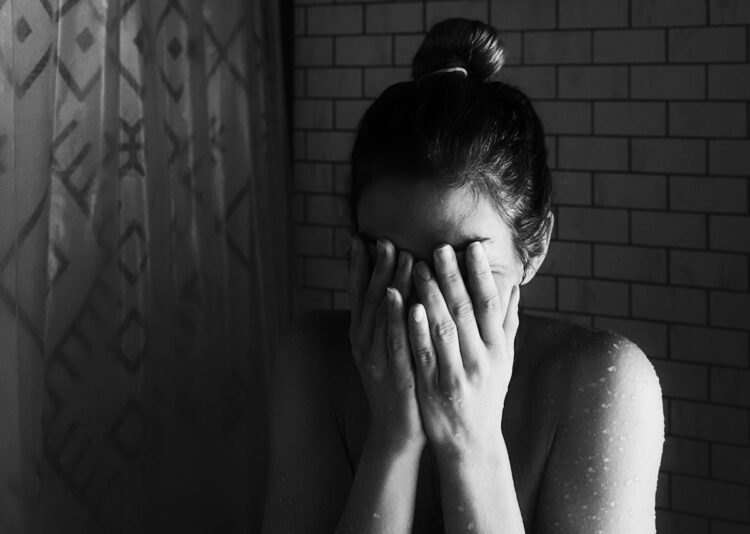 Grayscale photo of woman covering her face with her hands