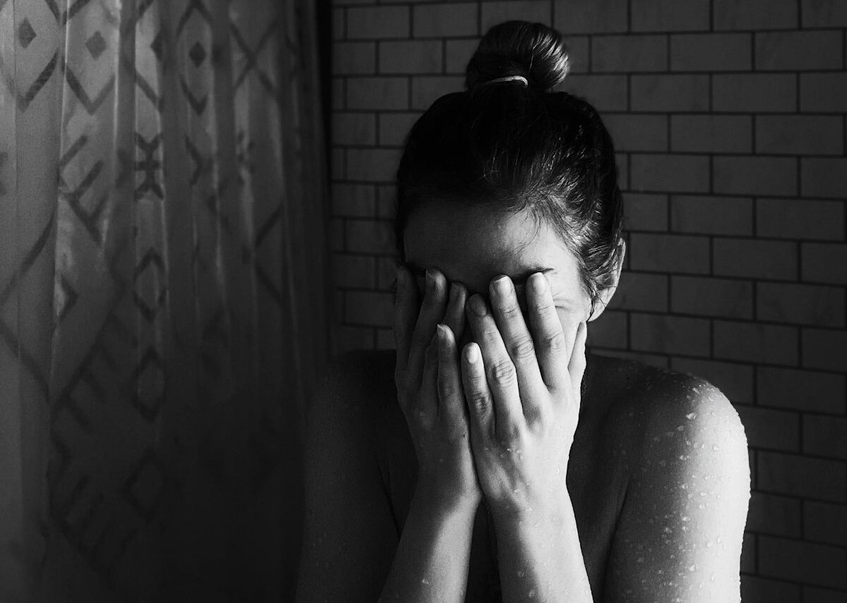 Grayscale photo of woman covering her face with her hands