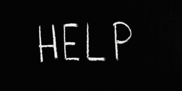 Chalk-written 'HELP' on a deep black background symbolizes assistance and encouragement.