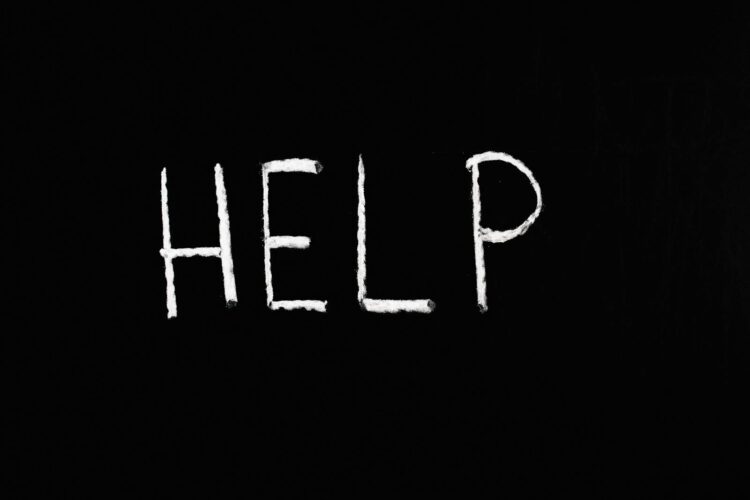 Chalk written 'help' on a deep black background symbolizes assistance and encouragement