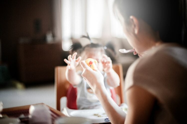 Selective focus photography of woman feeding baby