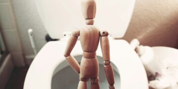 brown wooden mannequin on white ceramic toilet bowl