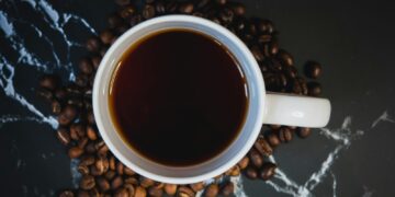 white ceramic mug with coffee on black and white textile
