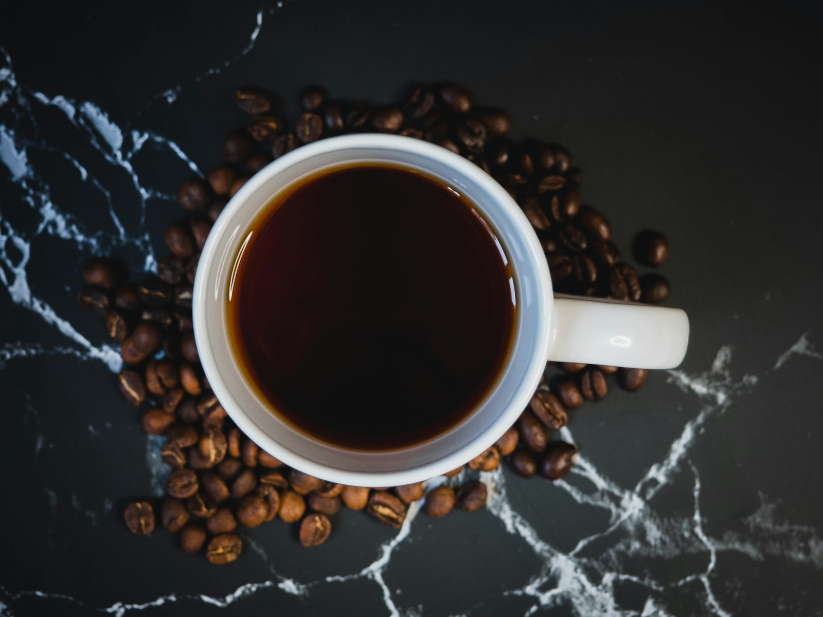 White ceramic mug with coffee on black and white textile